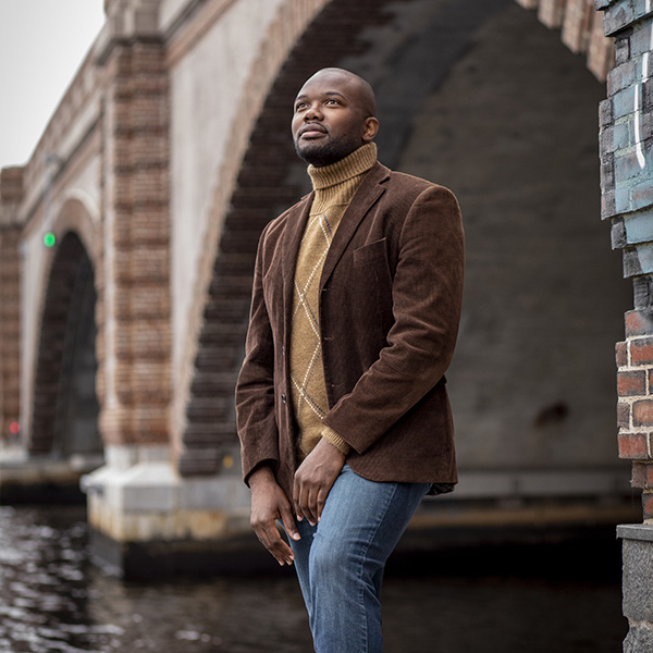 A man stands by a bridge near water