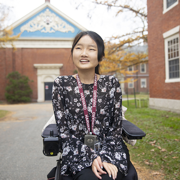 A student using a wheelchair on a walkway near brick buildings