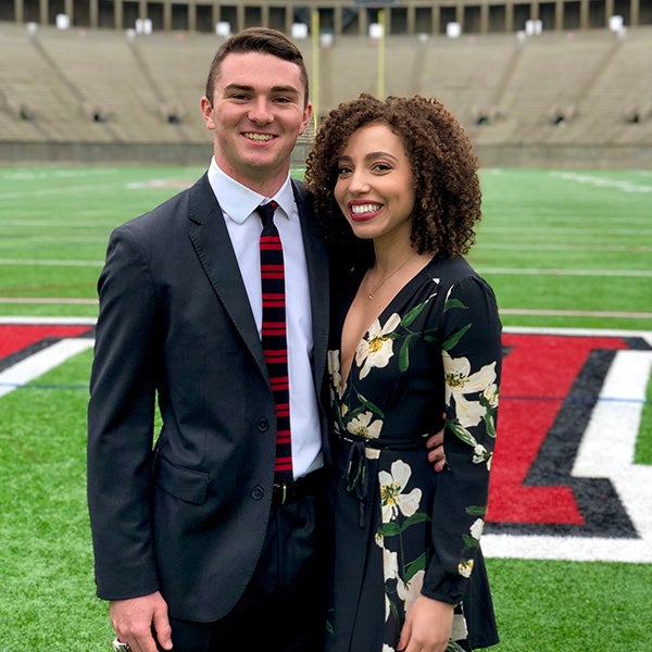 Two students standing together on the football field at Harvard dressed in nice clothing