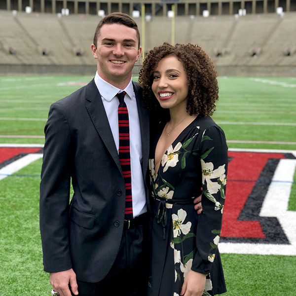 Two students standing together on the football field at Harvard dressed in nice clothing