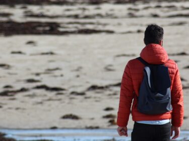 A teenager wearing a backpack looks out into the distance