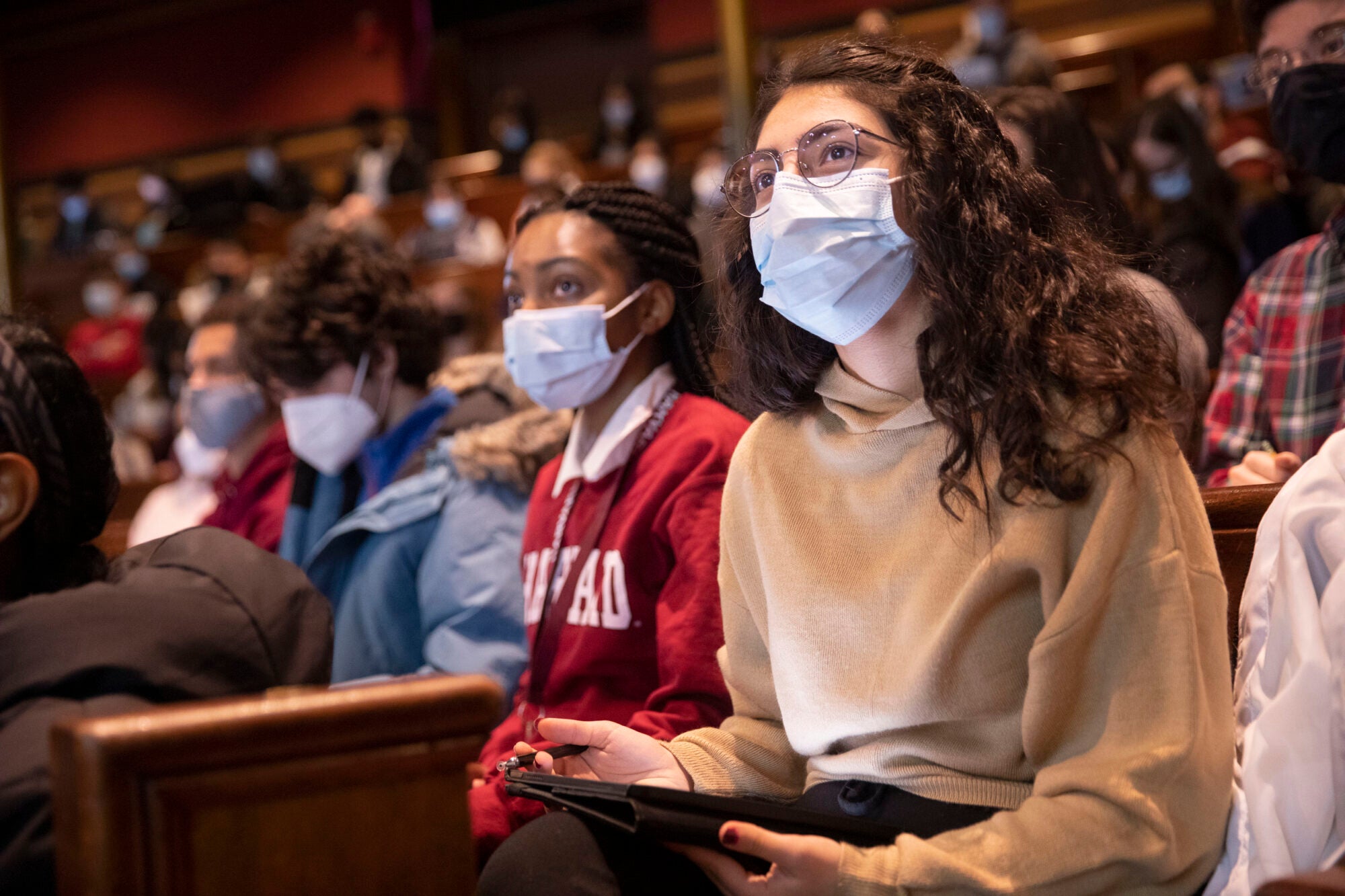 Two students wearing masks sit in a large classroom