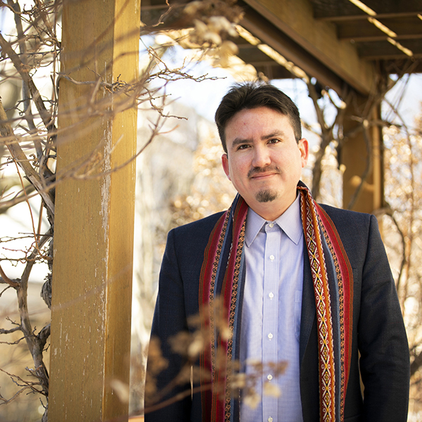 A man stands outside with winter trees around him