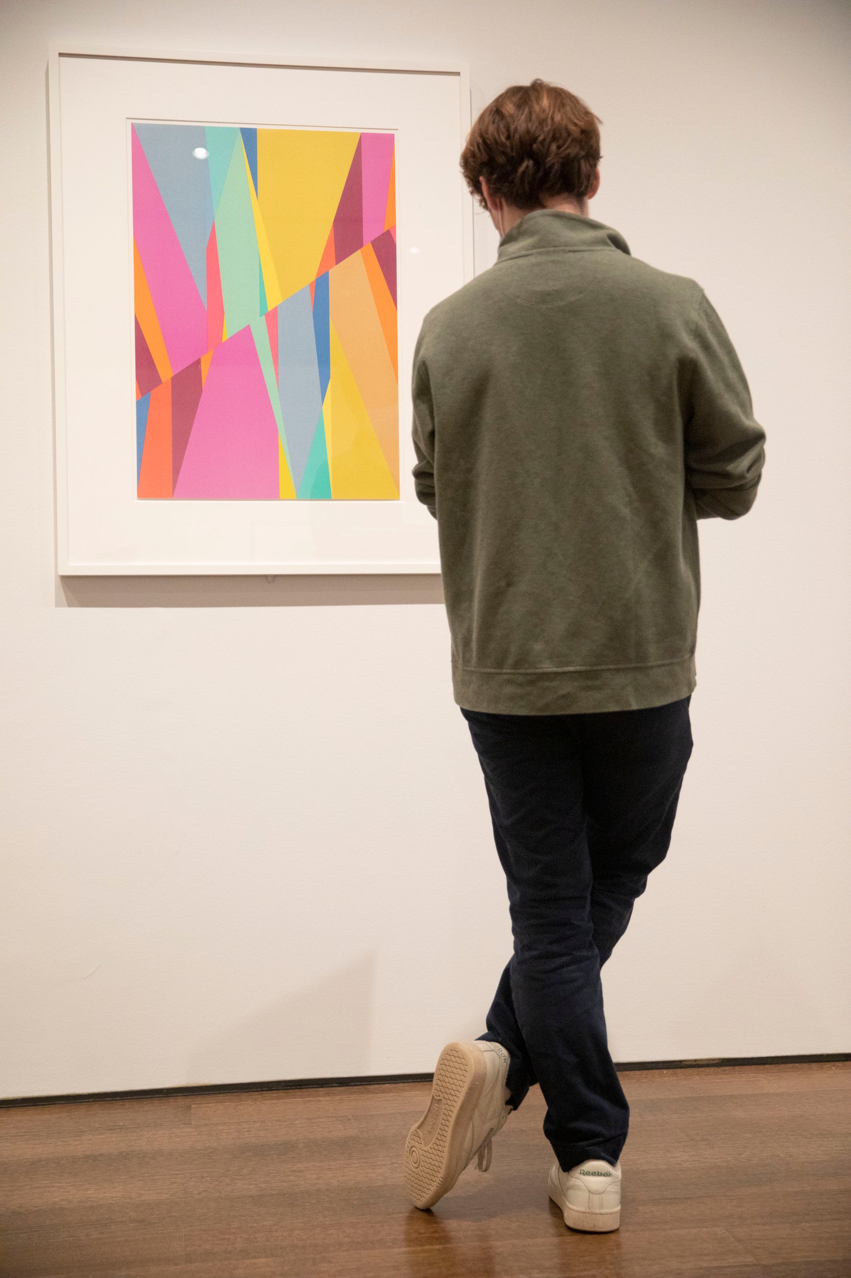A student in a museum looks at a piece of artwork on the wall