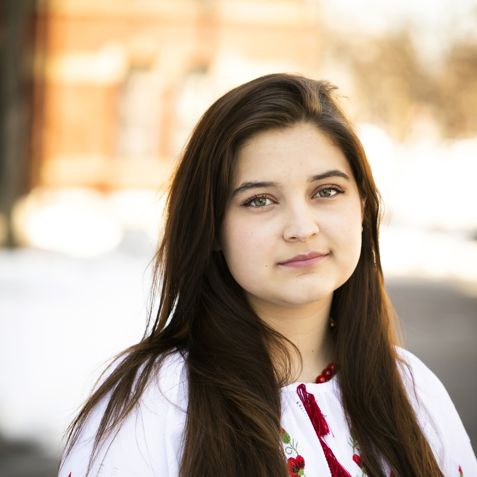 A student with long dark hair stands outside