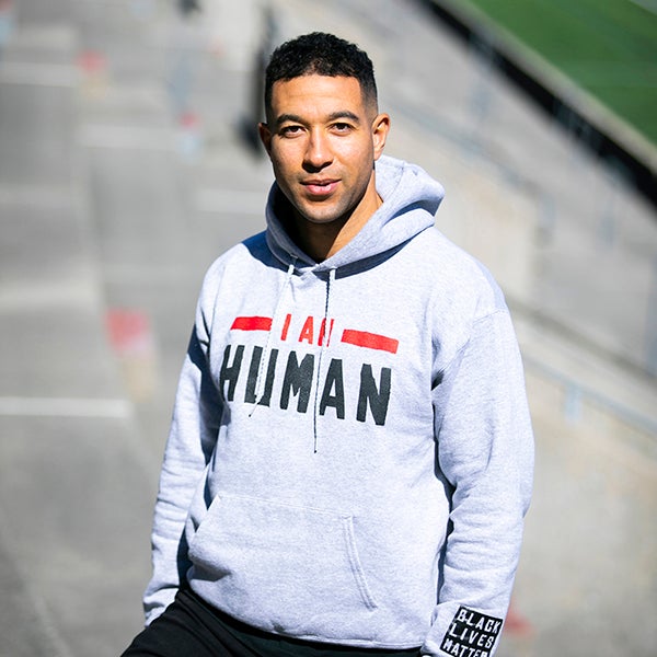 A young man wearing a grey sweatshirt on the steps of a stadium