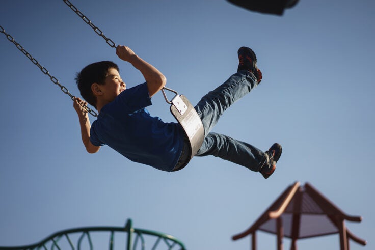 A young boy plays on a swing set