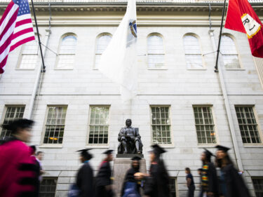 People walking past the John Harvard statue