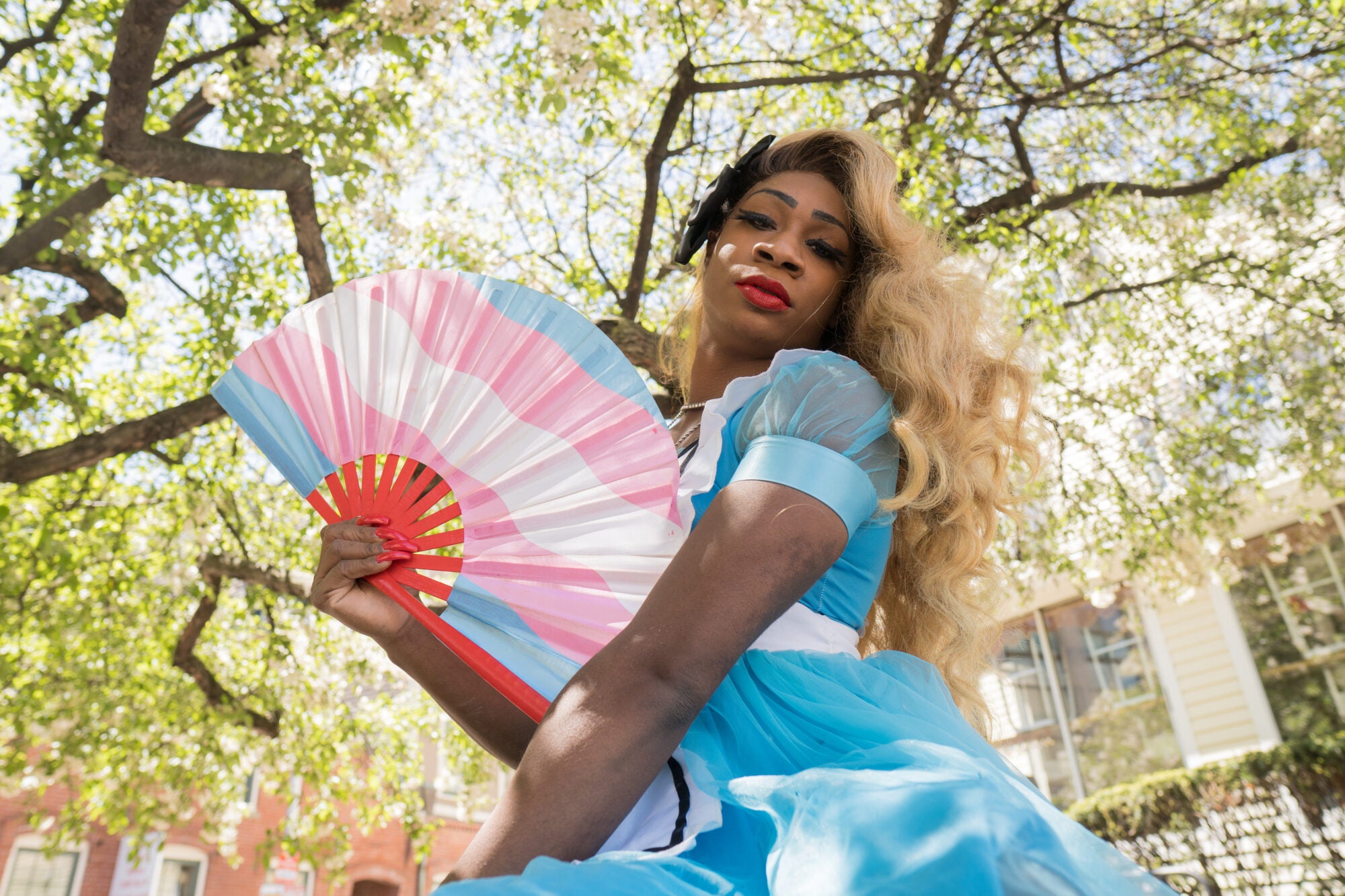 A performer dressed in an "Alice in Wonderland" costume poses with a fan