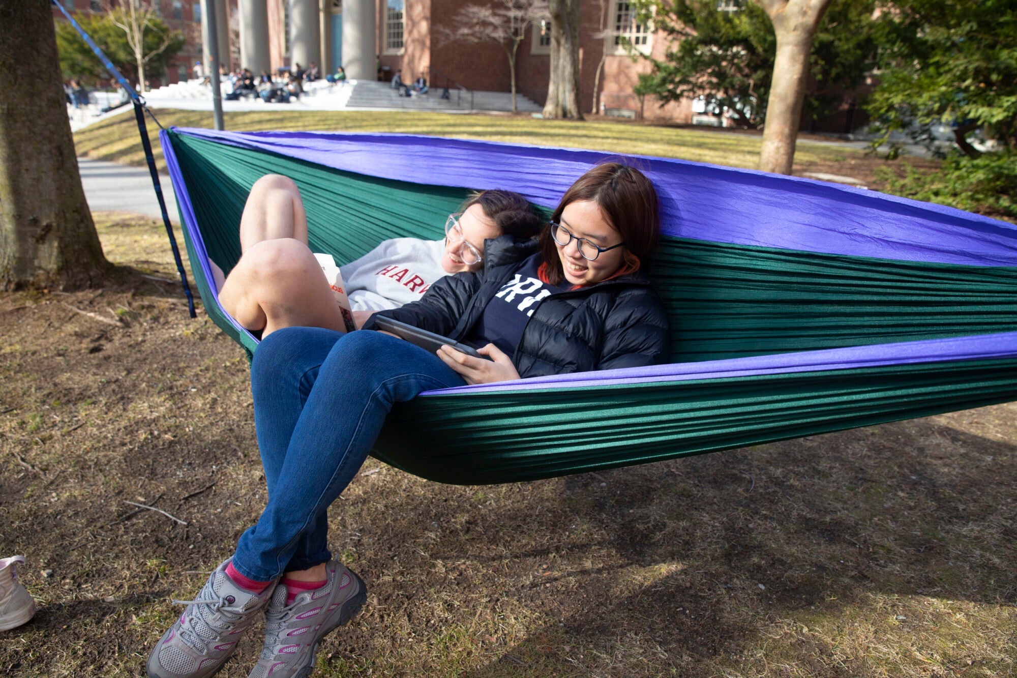 Two students laying in a hammock reading