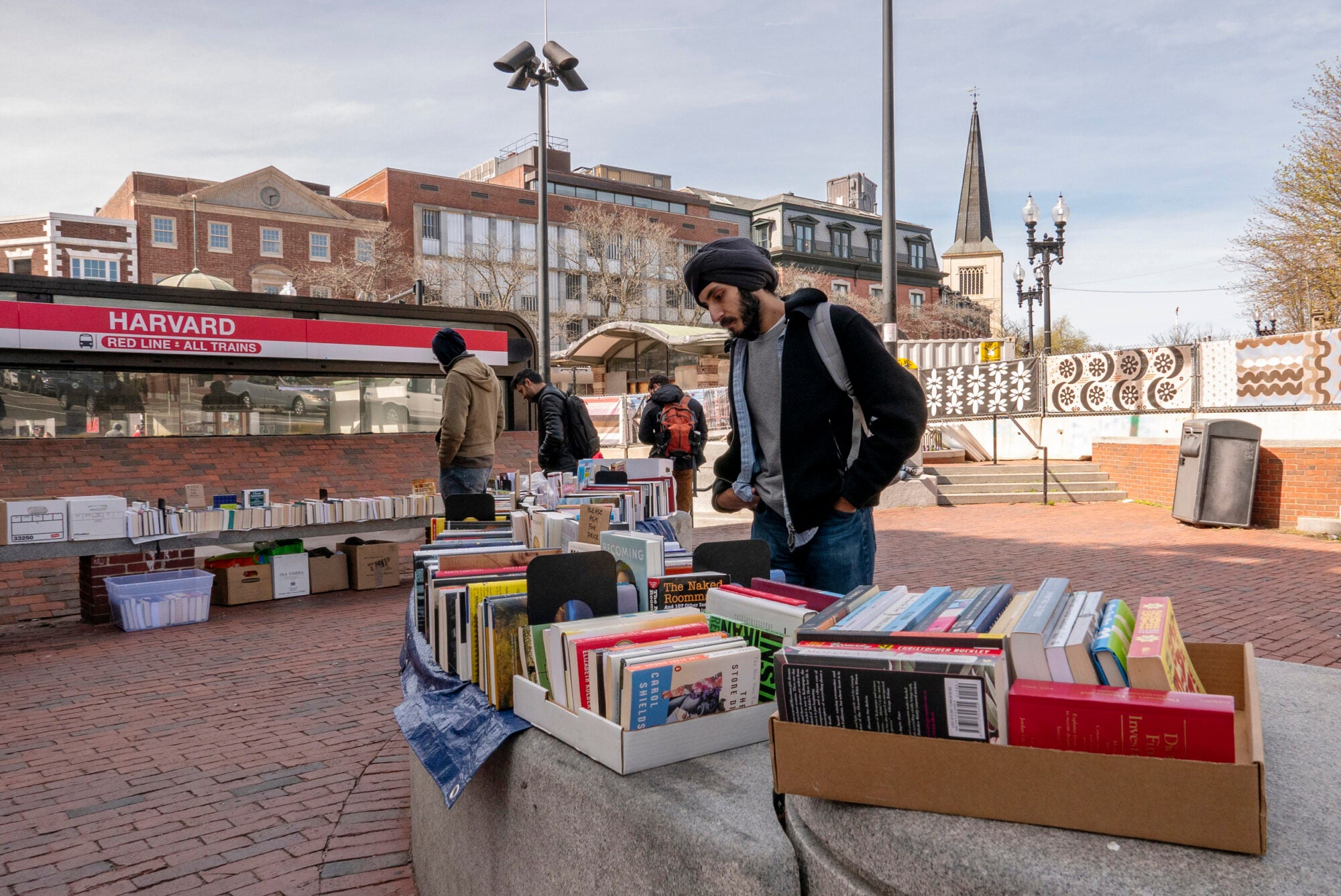 A man sorts through a box of books outside of a train stop
