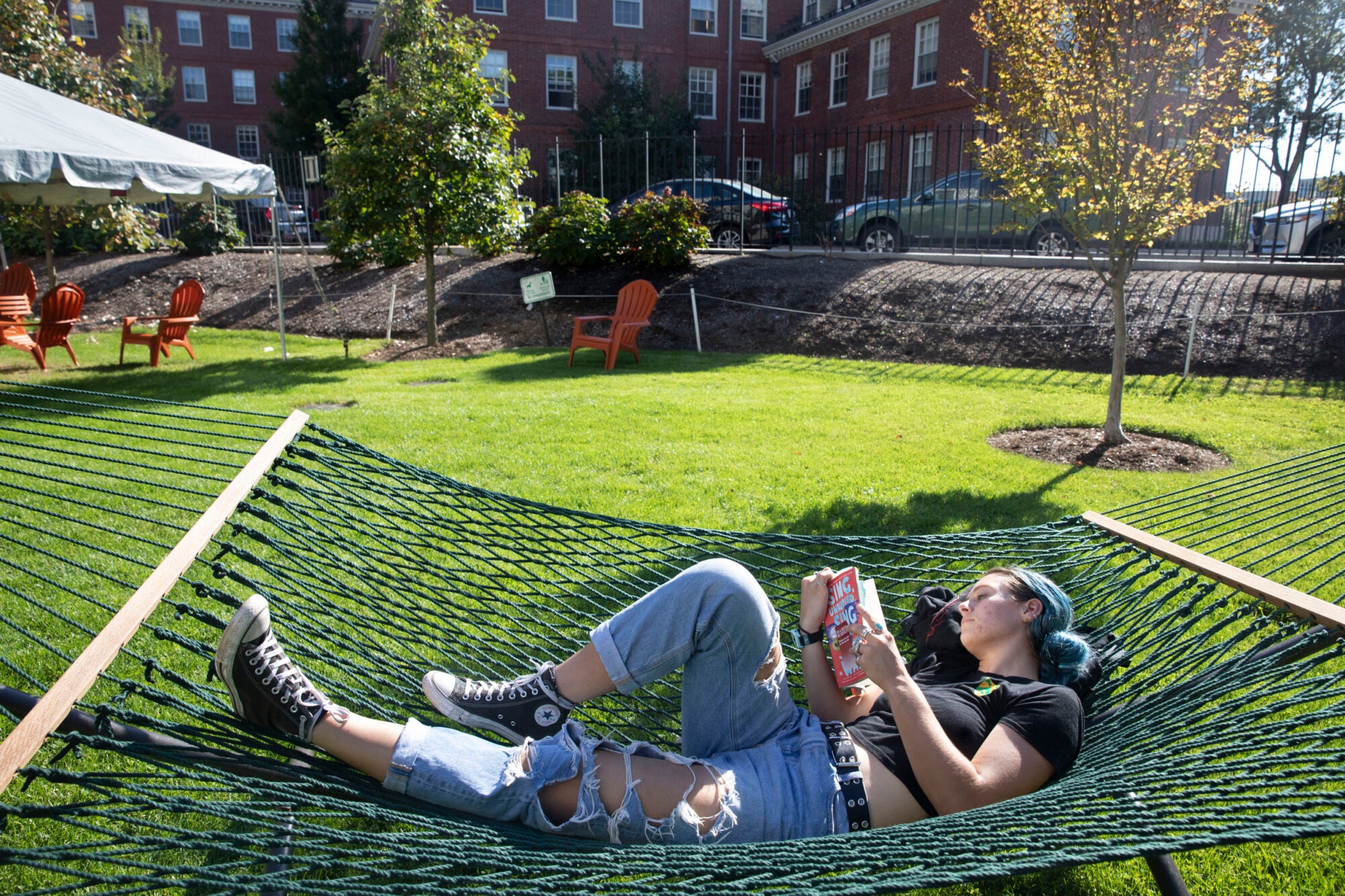 A student lays in a hammock with a book