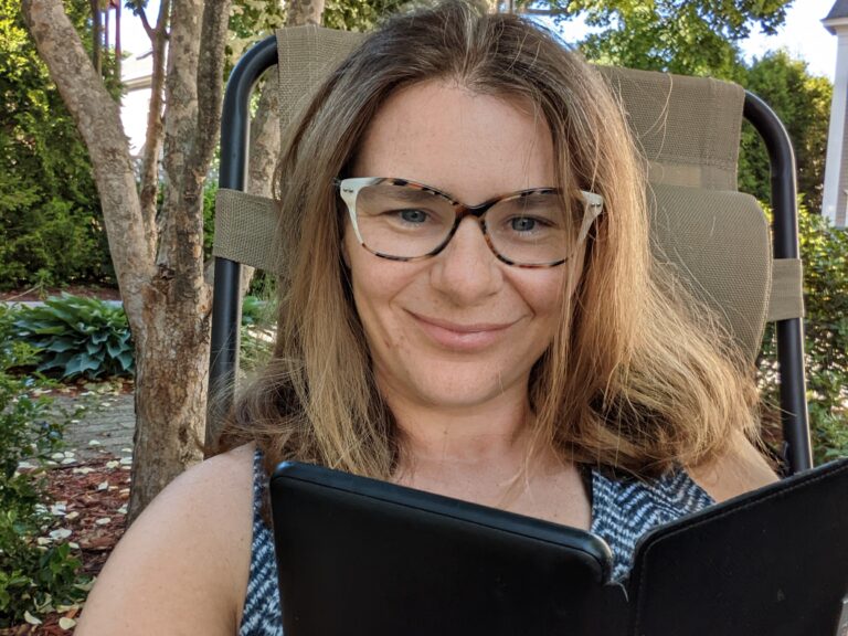 A woman reads a kindle outside