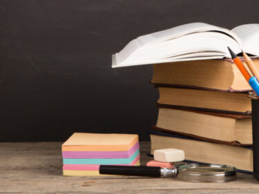 A desk with books, pens, and sticky notes