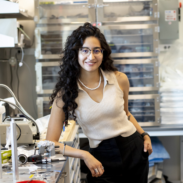 A young woman leans on a bench in a lab