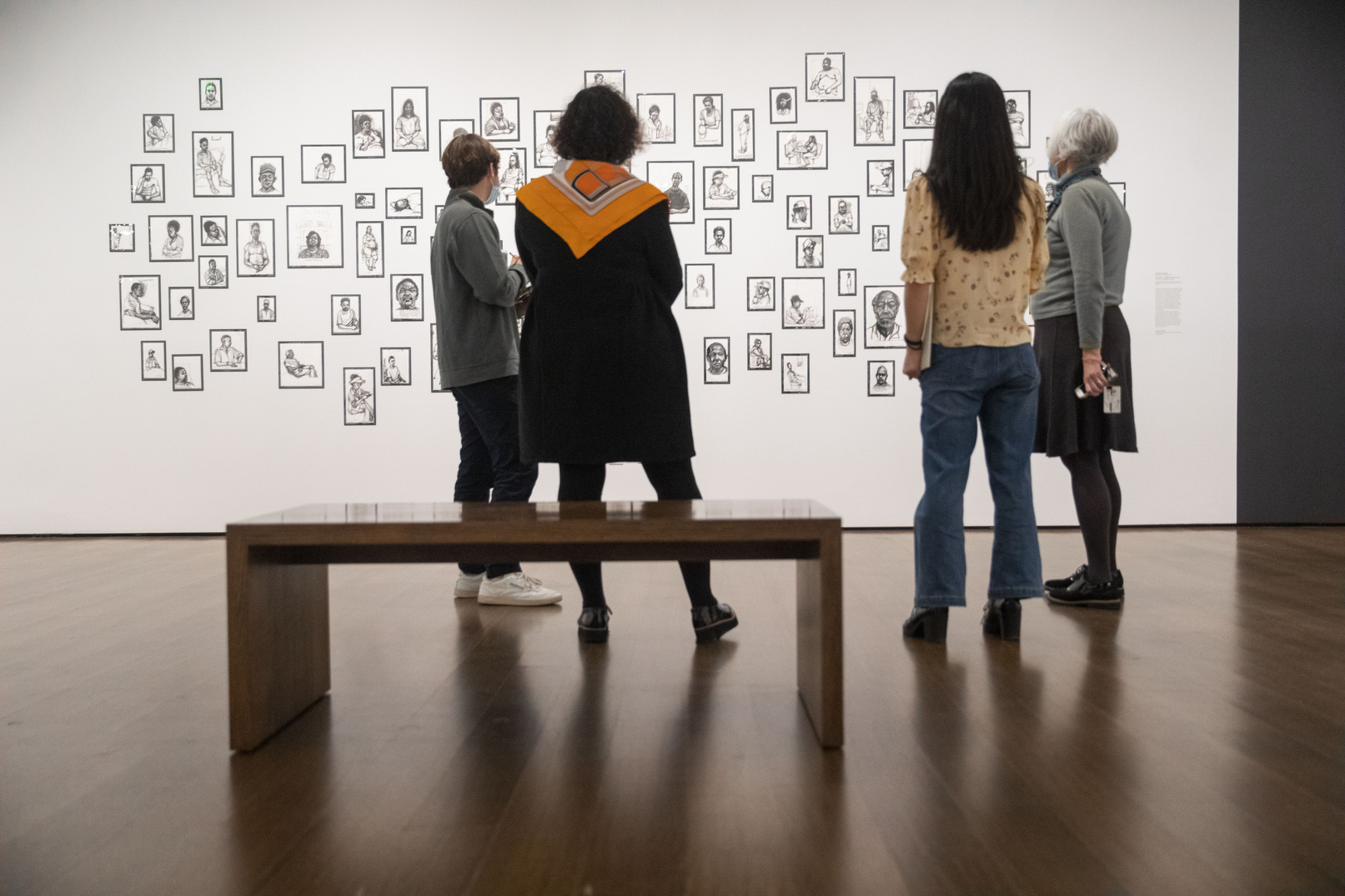 people looking at paintings on a wall