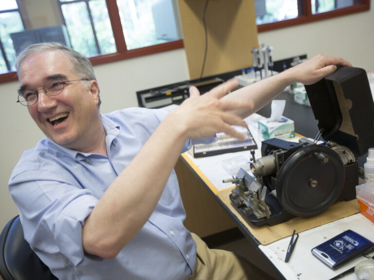 A person smiling next to a sample slicer