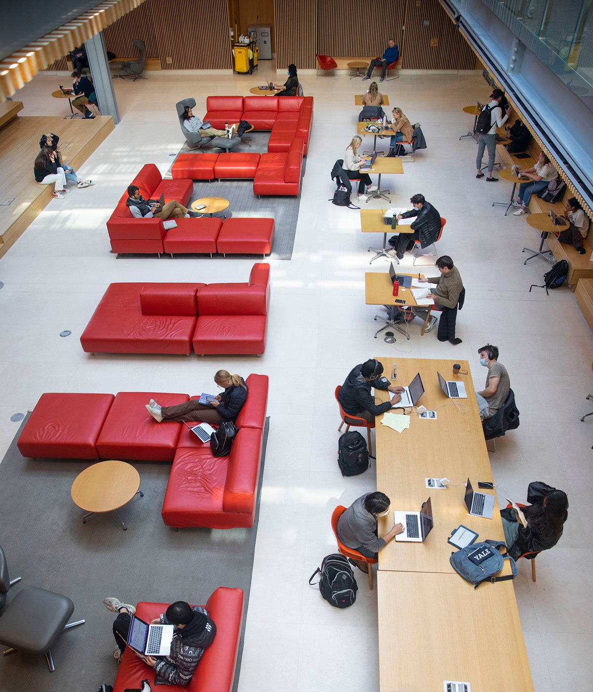 Students study at large tables and on red couches in the student union
