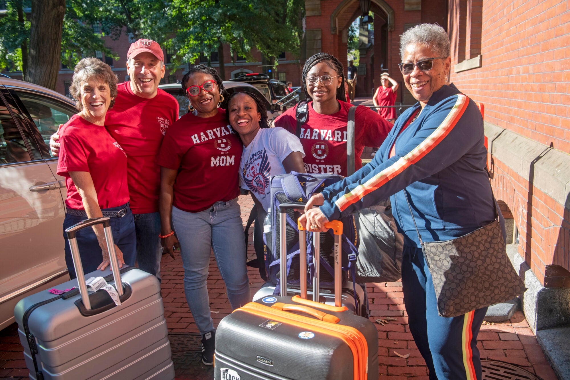 A student poses with her family and Harvard President Larry Bacow as they unload her car on move-in day