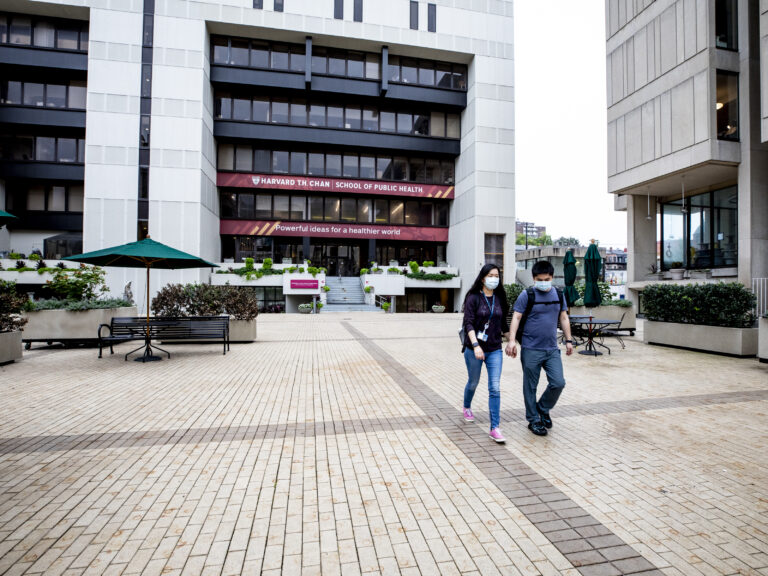 Two people walking away from the Harvard Chan building