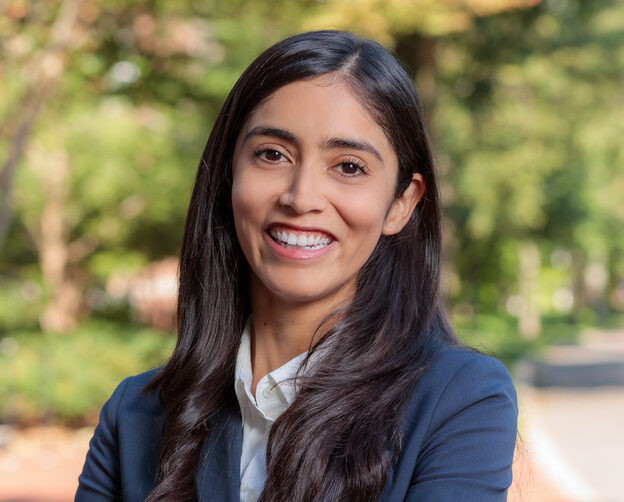 A woman wearing a blazer stands outside