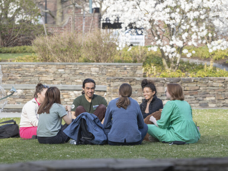 People sit in a circle outside on a lawn