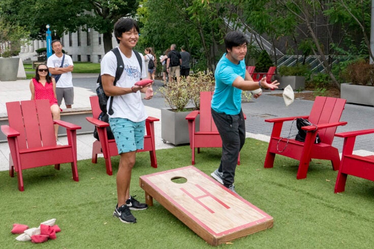 Two people play corn hole together outside