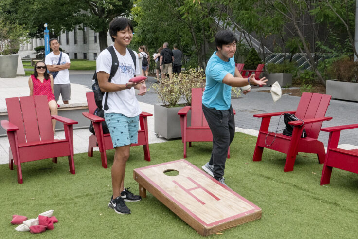 Two people play corn hole together outside