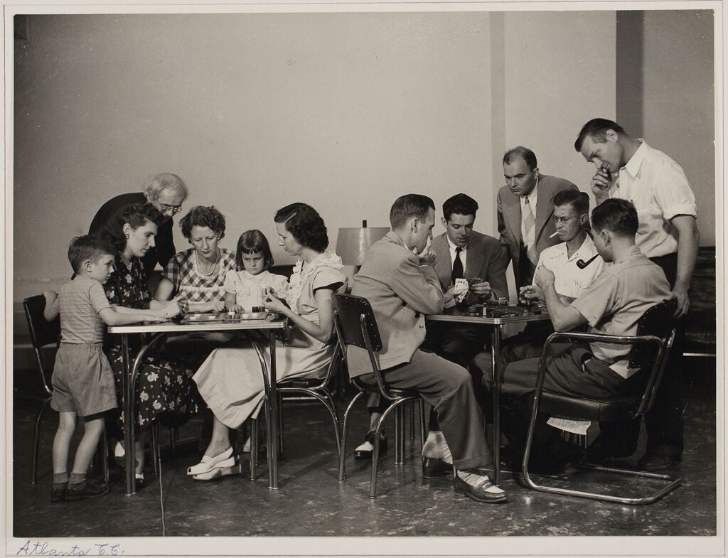 A black and white photo of people playing checkers and chess