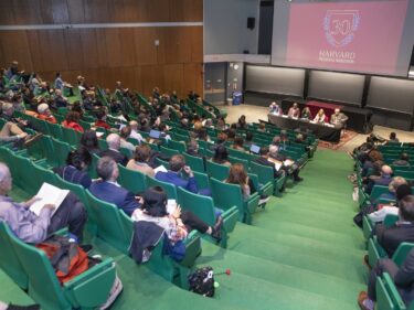 stadium-seating lecture hall with a projection of the inauguration graphic at the front of the class.