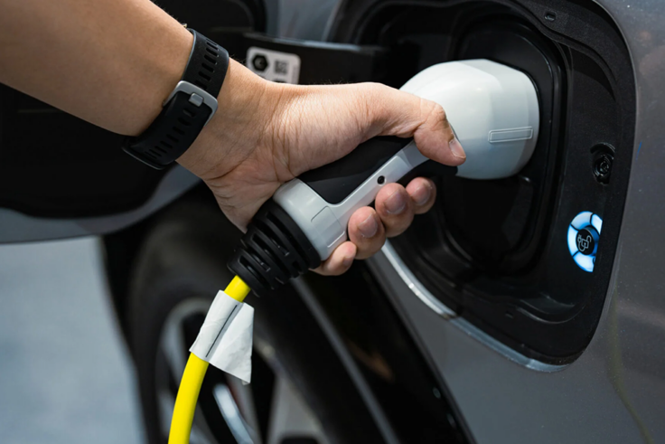 A person plugs an electric vehicle charger into the charging port