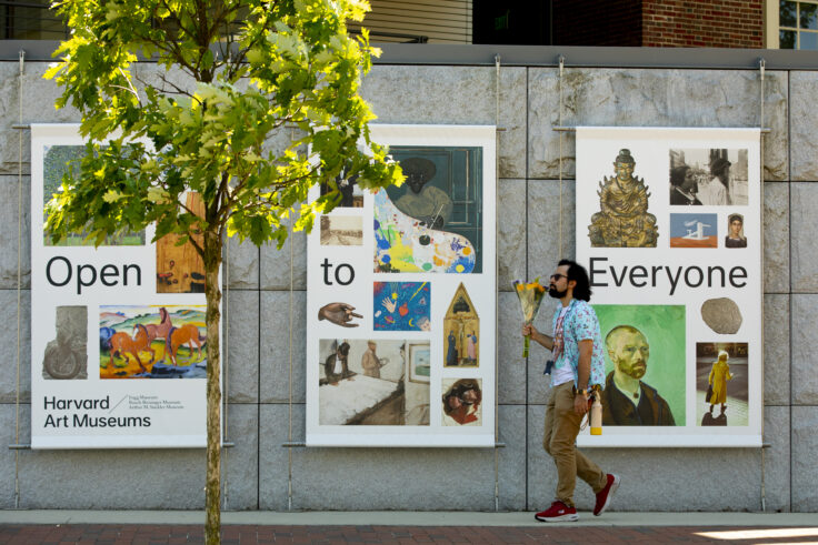A person walking by signs that say "Open to Everyone"