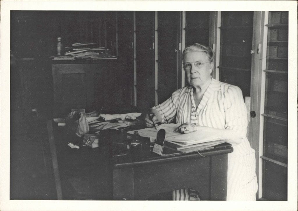 A black and white photo of a woman at a desk