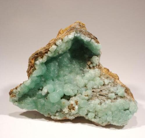 A rock with green fuzzy crystals inside