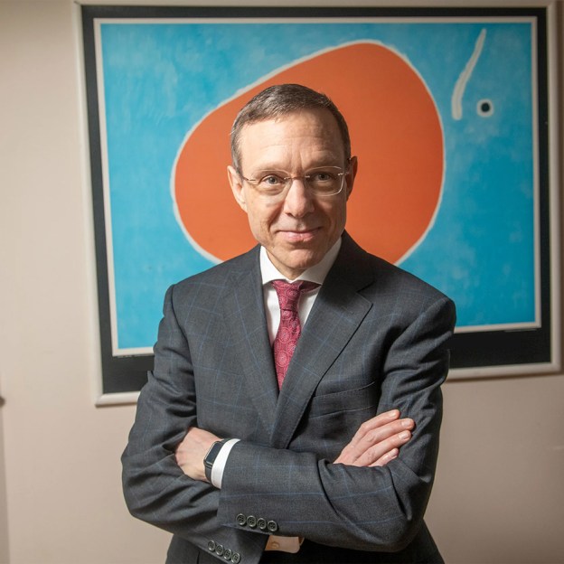 Avi Loeb posing in front of a piece of artwork