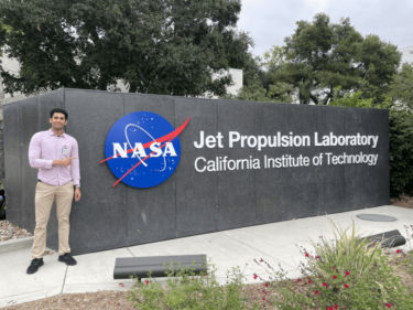 Rohil Dhaliwal in front of a sign for NASA’s Jet Propulsion Laboratory in Pasadena