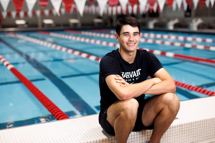 A swimmer sits on the edge of an indoor pool.