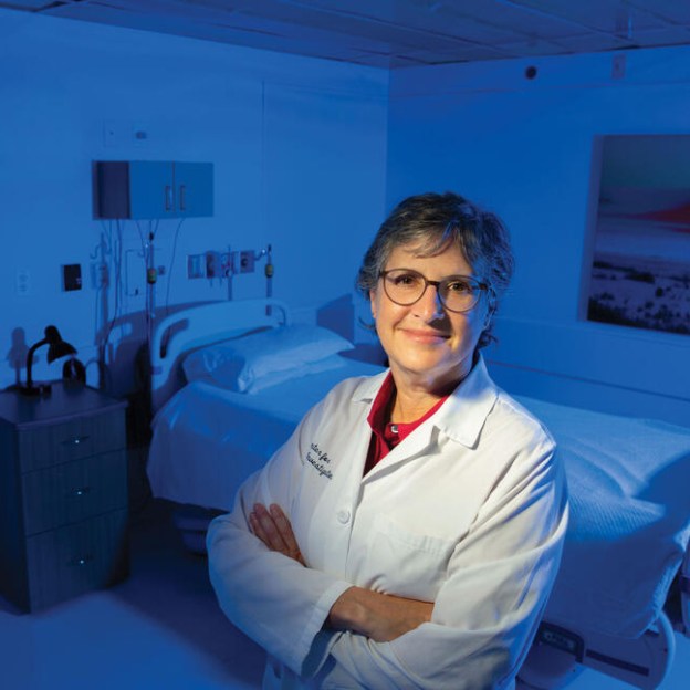 A woman wearing a white medical coat in a hospital room
