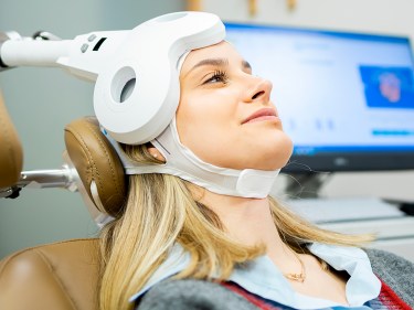 A woman wearing a transcranial magnetic stimulation (TMS) device