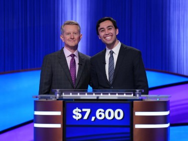 A contestant and host on the Jeopardy set.