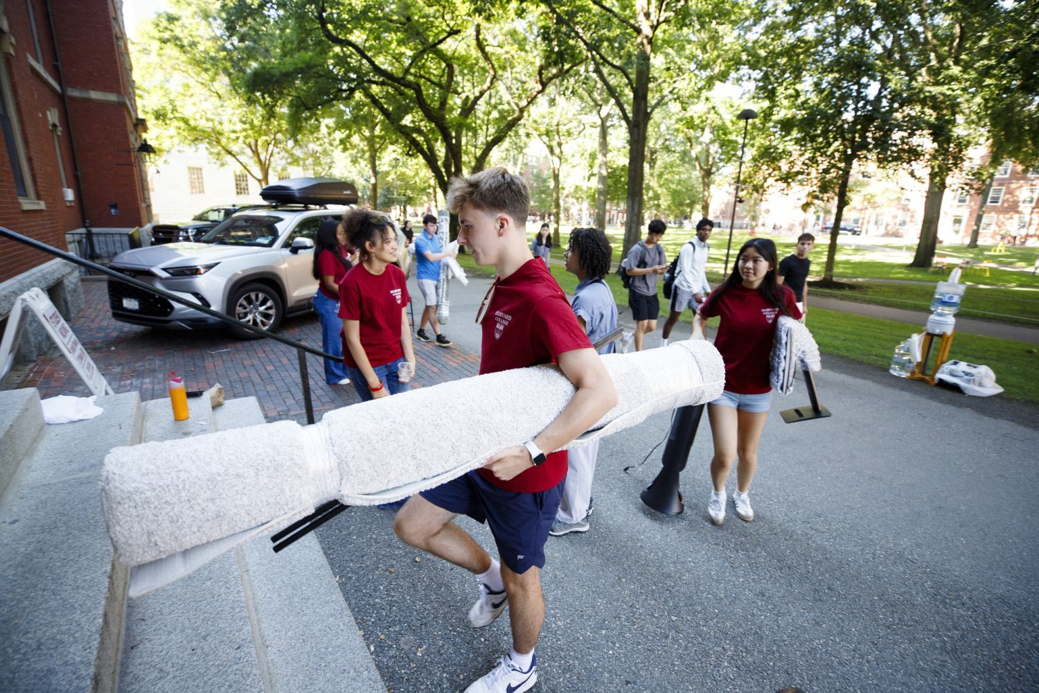 A student carries a rolled up rug on move in day.